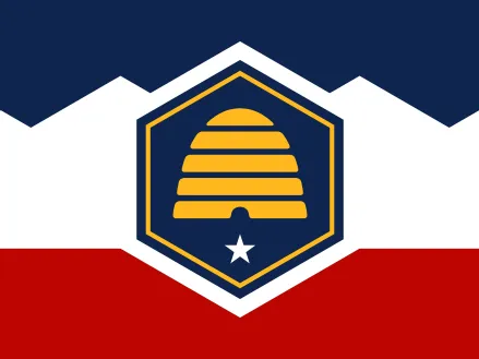 New flag for the state of Utah: Rectangle divided into three sections by two lines, with blue on top, white in the middle housing a blue hexagon outlined in gold with a gold beehive inside, a white five-pointed star below, and red at the bottom.